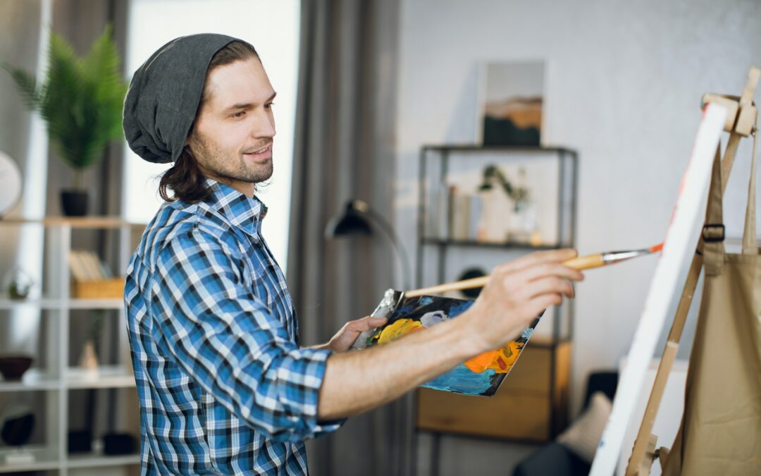 Man drawing with brush on canvas at art studio