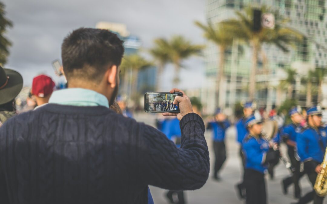 Man taking cell phone photo of a parade