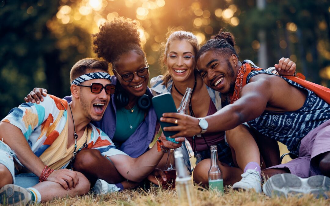 Multiracial group of happy festival goers taking selfie with mobile phone.