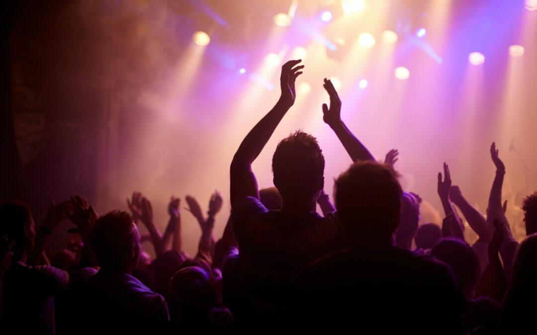 Rock on. Rear view of a music fan dancing with her arms raised at a music concert.