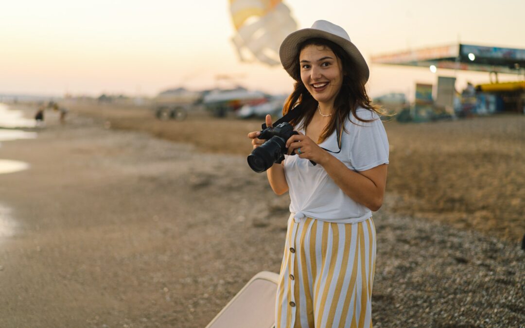 Traveling and photography. Young woman with a camera is photographed on the sea beach.